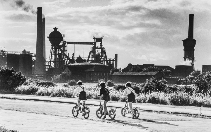 Three boys on wheels against an industrial backdrop